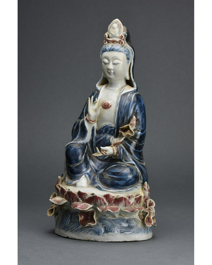 CHINESE PORCELAIN GUANYIN FIGURE: Ca.1644-1911; Qing dynasty or later. This superb porcelain figurine shows the bodhisattva of compassion, seated on a double-lotus base with the right knee raised and the left leg crossed before the bo