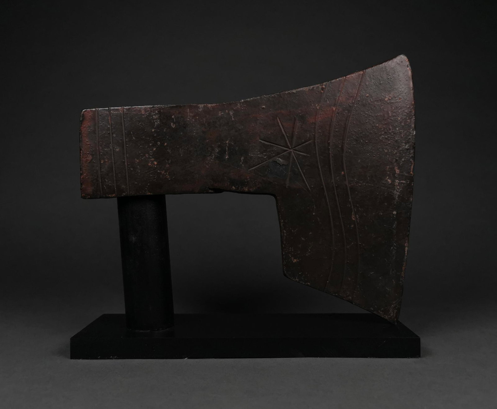 VIKING IRON AXE WITH DECORATION ON STAND: c. 900-1100 AD. Viking age. An iron bearded axe head with a heavy blade and a round socket. Etched decoration on one side includes a star motif and undulating lines, and on the other a hatched design 