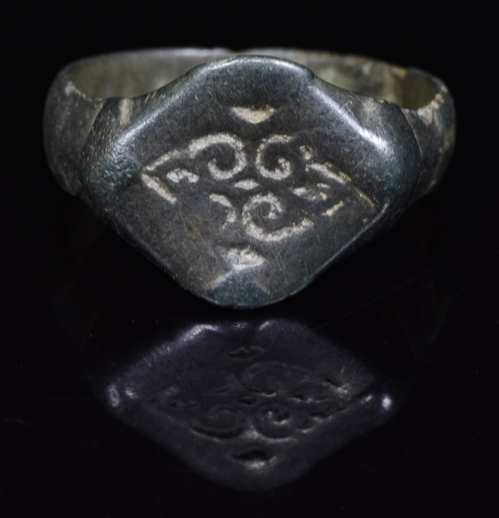MEDIEVAL DECORATED BRONZE RING: 1000-1200 AD, Medieval. Bronze ring with circular hoop and diamond-shaped bezel featuring engraved decoration in the form of two confronted hearts, perhaps reflecting the items use as a marriage or we