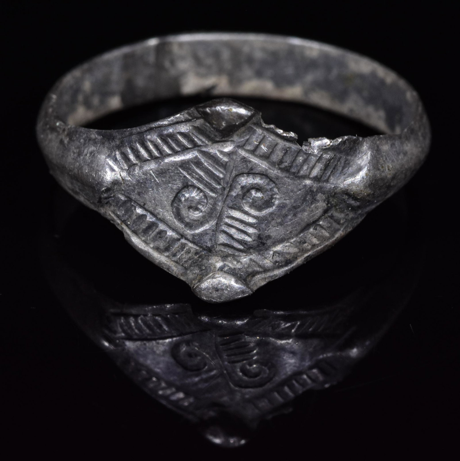 VIKING ERA SILVER RING WITH SYMBOLS: C. 900-1100 AD. Viking Period. This beautiful silver ring comprises a circular hoop and a lozenge-shaped bezel with incised linear and curvilinear decoration (possibly a runic symbols). This simple 