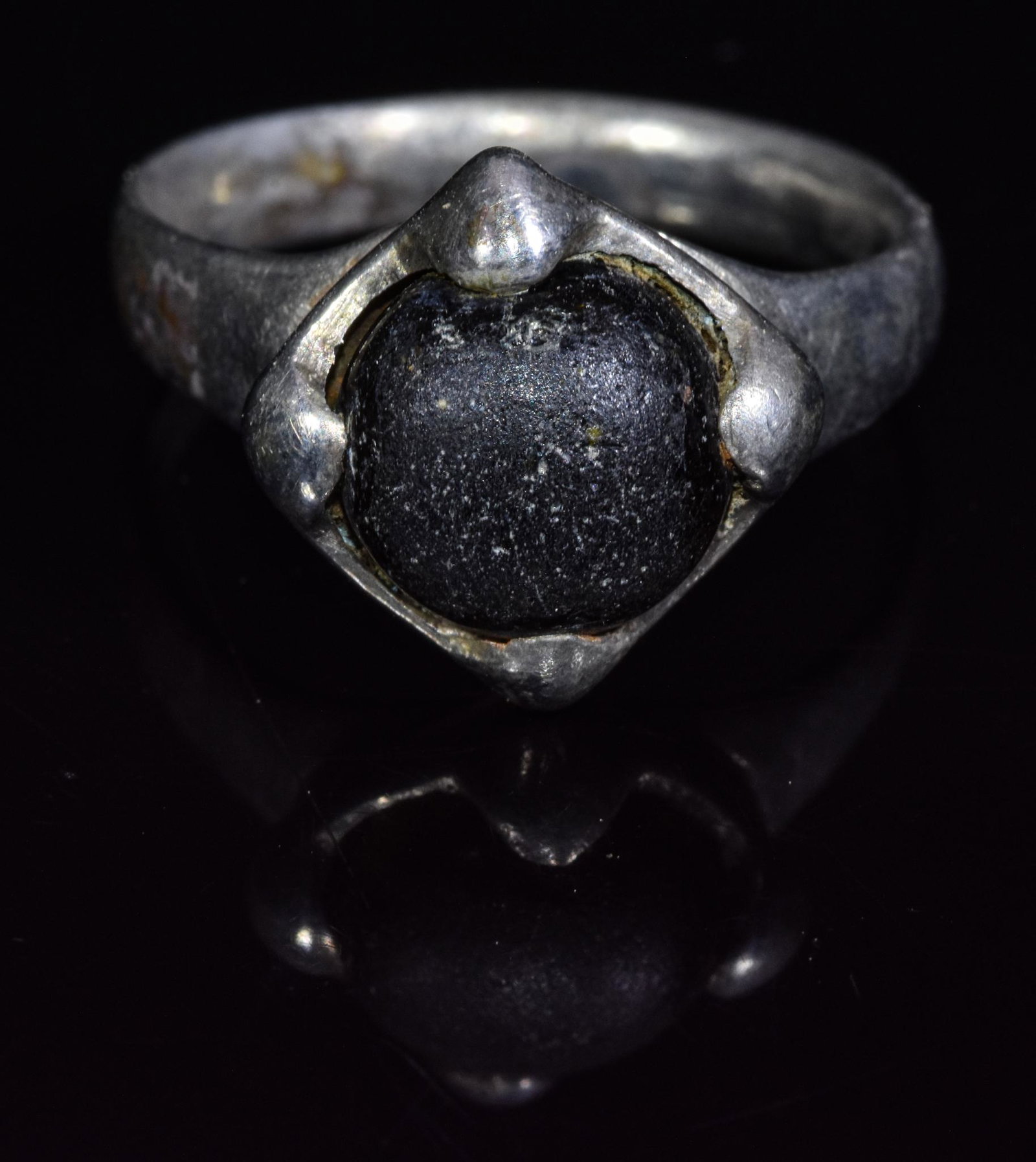 VIKING ERA SILVER RING WITH CABOCHON: C. 900 AD, Viking Age. A silver D-shaped hoop enclosing a circular bezel, set with black glass cabochon secured by four additional 'arms.' This simple yet elegant ornament may have belonged to a Vikin