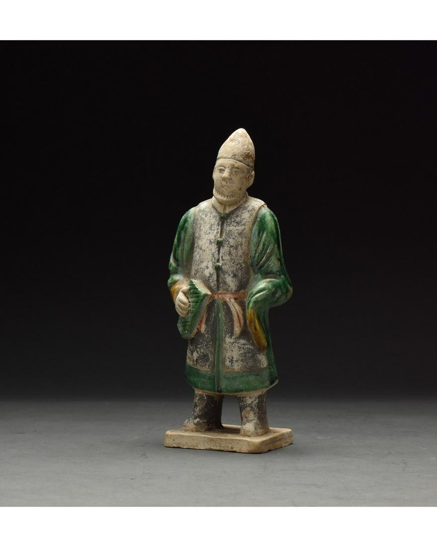 CHINESE MING DYNASTY GLAZED ATTENDANT FIGURE: Ca. 1368-1644 AD. Chinese Ming Dynasty Attendant Figure. An elaborately crafted male attendant figure dressed in a green tunic with vibrant yellow cuffs, a deep blue overtunic, which is belted with a 