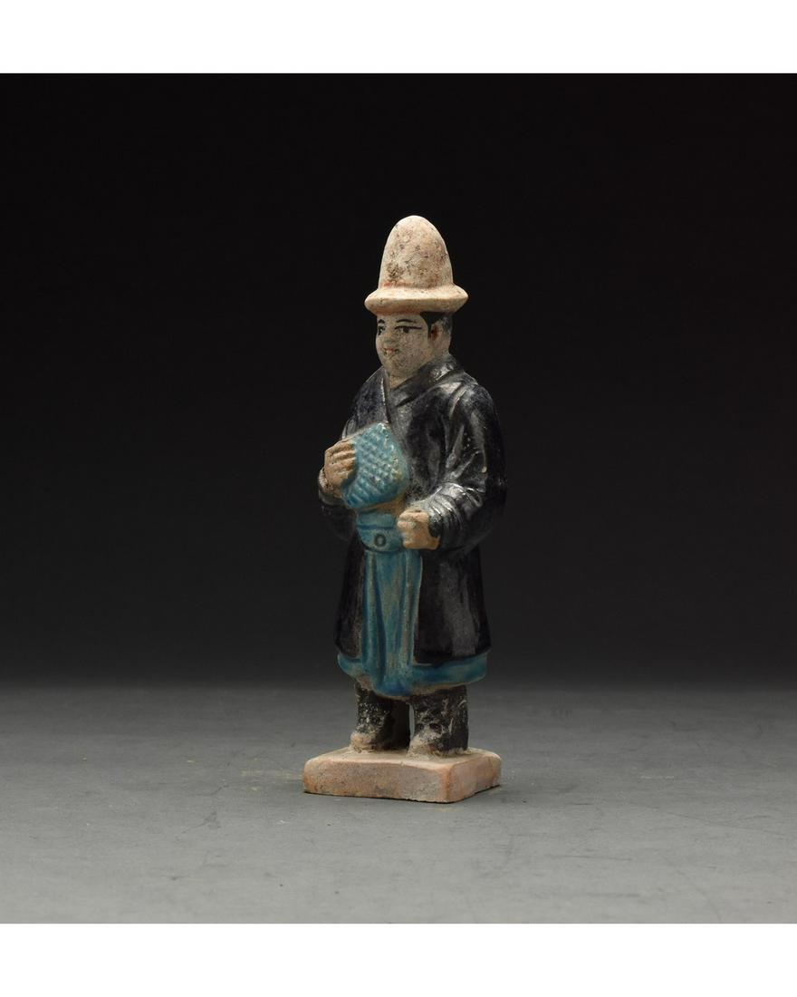 CHINESE MING DYNASTY GLAZED ATTENDANT FIGURE: Ca. 1368-1644 AD. Chinese Ming Dynasty Attendant Figure. An elaborately crafted male attendant figure dressed in a light blue tunic, a black overtunic which is belted with a light blue sash and a tall