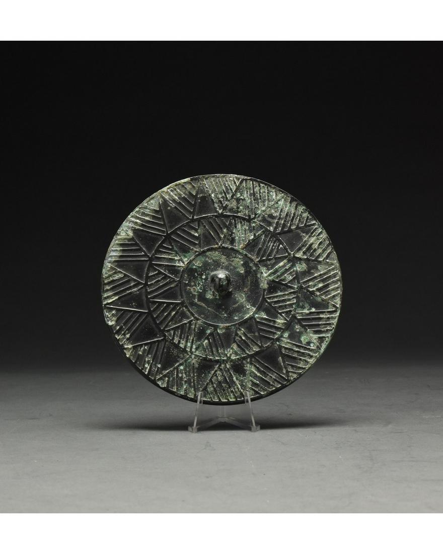 CHINESE HAN DYNASTY BRONZE MIRROR: Ca. 202 BC–220 AD. Han Dynasty or later. Circular bronze mirror with a repeating concentric star motif. The Han Dynasty, which ruled between 202 BC–220 AD, brought great prosperity and stability t