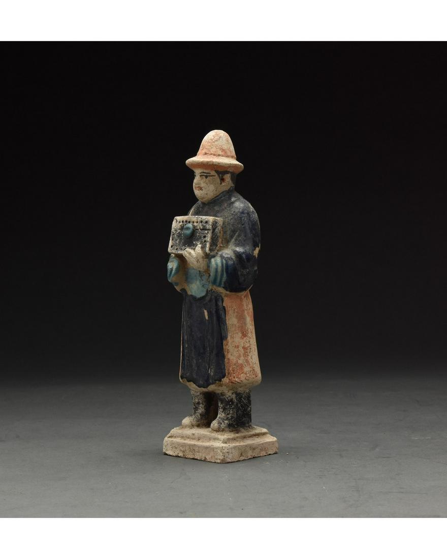 CHINESE MING DYNASTY GLAZED ATTENDANT FIGURE: Ca. 1368-1644 AD. Chinese Ming Dynasty Attendant Figure. An elaborately crafted male attendant figure dressed in a light blue tunic, a dark blue overtunic which is belted with a light blue sash, and a