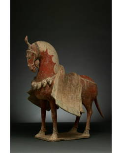 CHINA, NORTHERN WEI DYNASTY POTTERY CAPARISONED HORSE -: C. 386-534 AD. Northern Wei Dynasty. A painted pottery figure of a caparisoned horse. The horse stands foursquare with its head drawn inwards, and its tail lowered. Its pelt is picked out in a