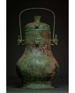 CHINA, WESTREN ZHOU DYNASTY WINE RITUAL YOU VESSEL -: 1045–771 BC. Western Zhou Dynasty. A bronze wine vessel known as a You, comprising a detachable domed lid with cylindrical handle top, piriform body, flaring foot and strap handle. The object