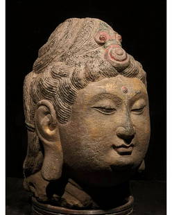 CHINA, TANG DYNASTY GILDED STONE HEAD OF BUDDHA: C. AD 618-907. Tang Dynasty. Stone head of Buddha with characteristic elaborate coiffured, two-tiered black “snail-shell” hair curls ornamented with a red spiralling jewel. The Buddha’s full