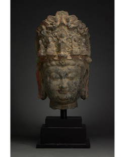 CHINA, TANG DYNASTY ELABORATE STONE HEAD OF BUDDHA: C. AD 618-907. Tang Dynasty. Grey stone head of Buddha with elaborate headdress. The Buddha’s hair is carefully modelled to allow us to distinguish individual curls, his heavily-lidded eyes are