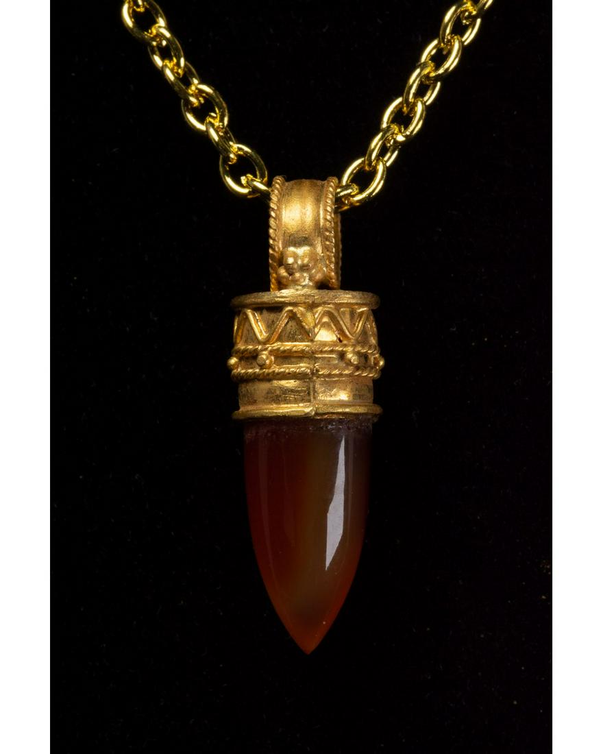 GREEK HELLENISTIC GOLD PENDANT WITH CARNELIAN STONE: c. 323-31 BC. Greek Hellenistic period. A gold pendant with a circular, ribbed suspension loop, cylindrical body and conical carnelian setting. The exteriors of the body and suspension loop are covere
