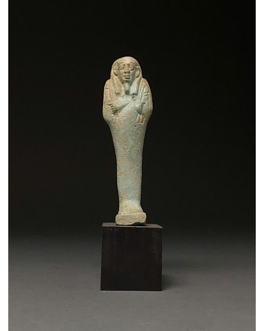 ANCIENT EGYPTIAN FAIENCE USHABTI: Ca.1070-945 BC Egyptian, Early Third Intermediate Period. Beautiful light blue faience ushabti figure wearing a tripartite wig and a false beard. Shabtis, also known as ushabtis, are Egyptian tomb off