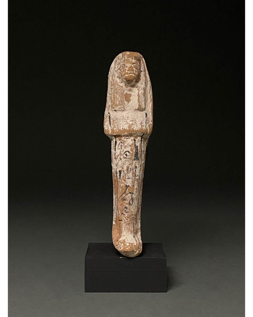 ANCIENT EGYPTIAN CERAMIC USHABTI: Ca.1070-945 BC Egyptian, Early Third Intermediate Period. Beautiful terracotta-coloured ceramic ushabti figure wearing a tripartite wig, a false beard and standing with crossed arms. Traces of white p