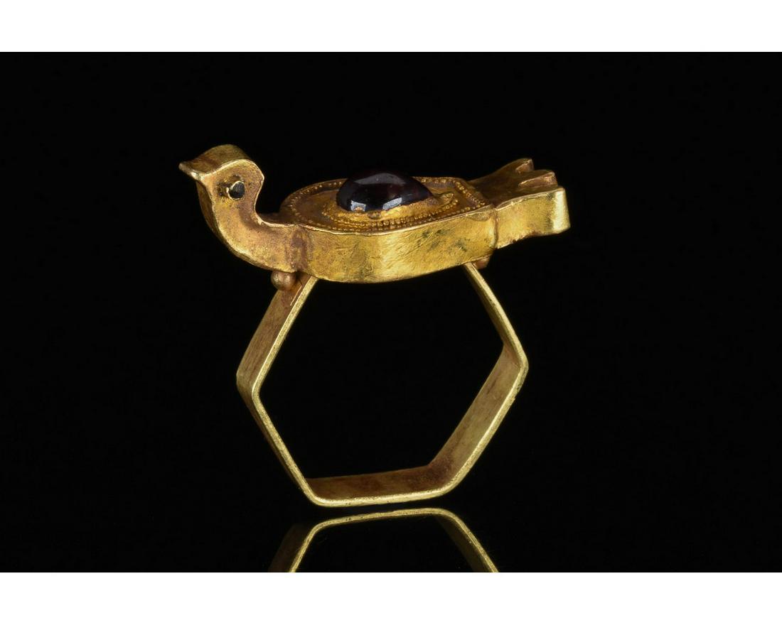 MEDIEVAL GOLD RING WITH BIRD AND GARNET - XRF TESTED: 600-900 AD. Byzantine. A rare medieval gold ring with a hexagonal hoop and zoomorphic bezel in the form of a bird in flight; the birdâ€™s back is decorated with a teardrop shaped garnet cabochon 