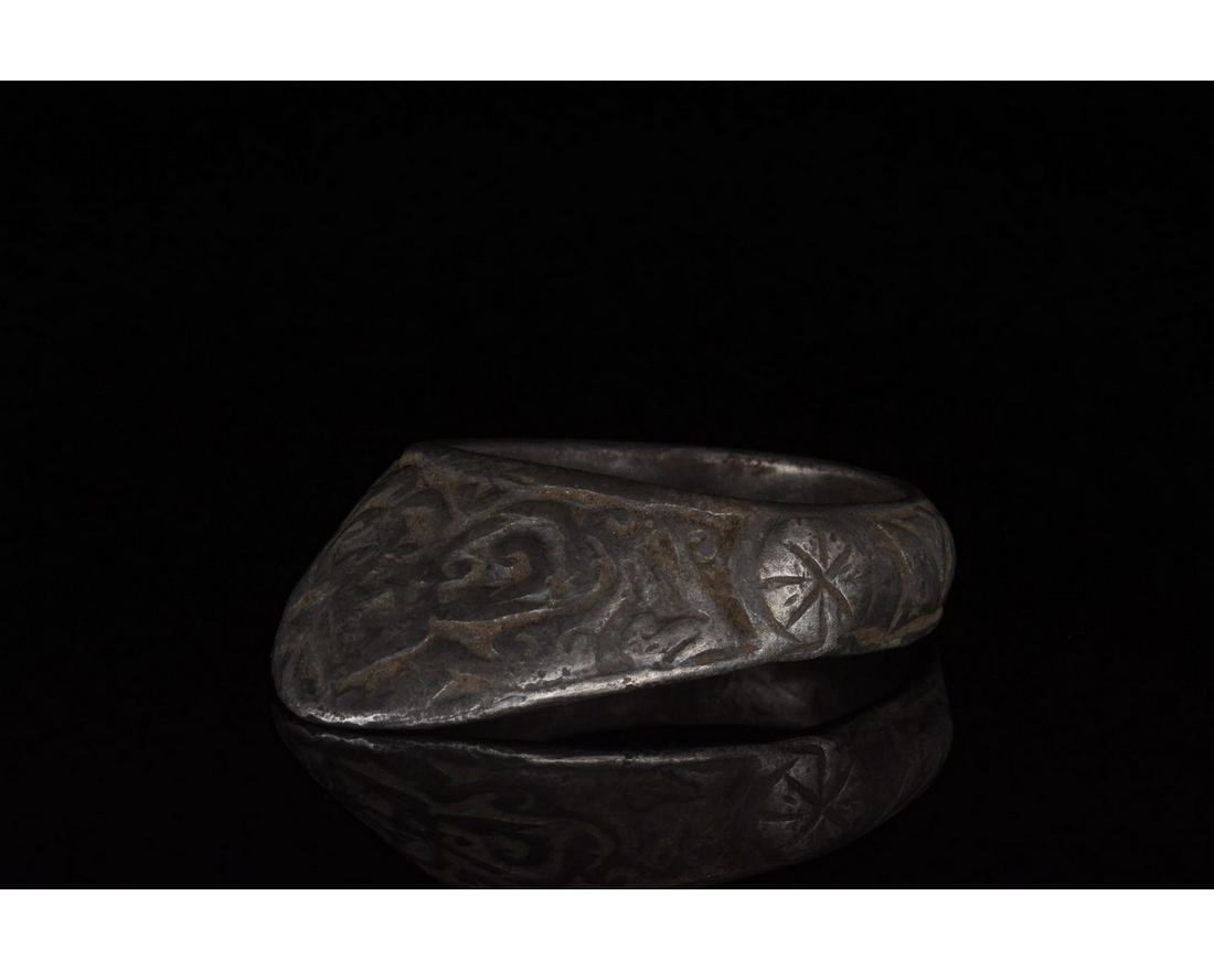MEDIEVAL SILVER ARCHER'S RING WITH DECORATION: Ca. 1200 AD, Medieval. A silver archerâ€™s ring comprising a circular hoop and projecting triangular guard. The exterior of the hoop and guard are covered in extensive incised geometric motifs. A