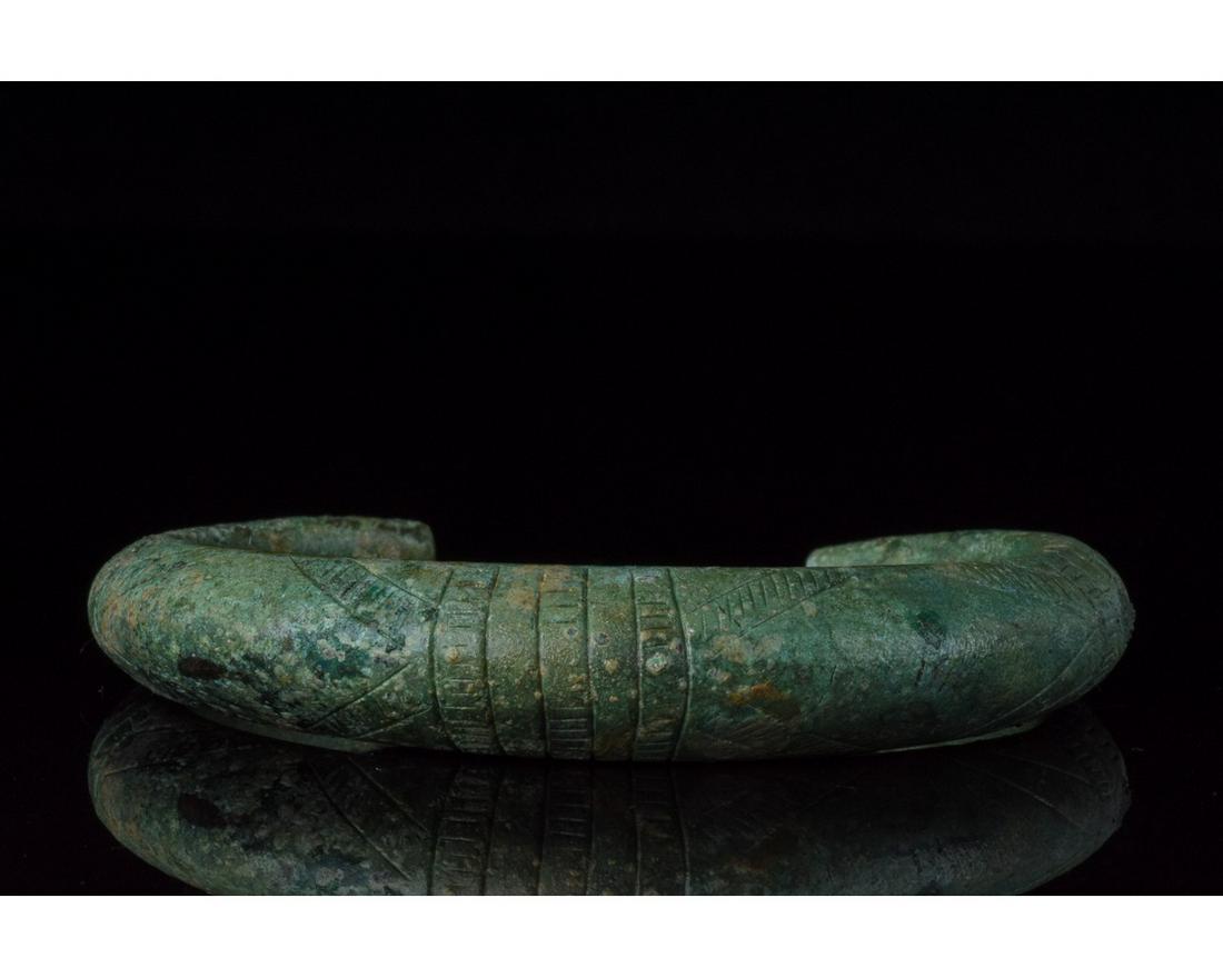 BRONZE AGE DECORATED BRACELET - STUNNING PATINA: 1000 â€“ 600 BC, Bronze Age. This thick and heavy cast bronze bracelet features a wide band with a D-shaped section and incied linear decoration. In the Bronze Age bracelets were used not only as