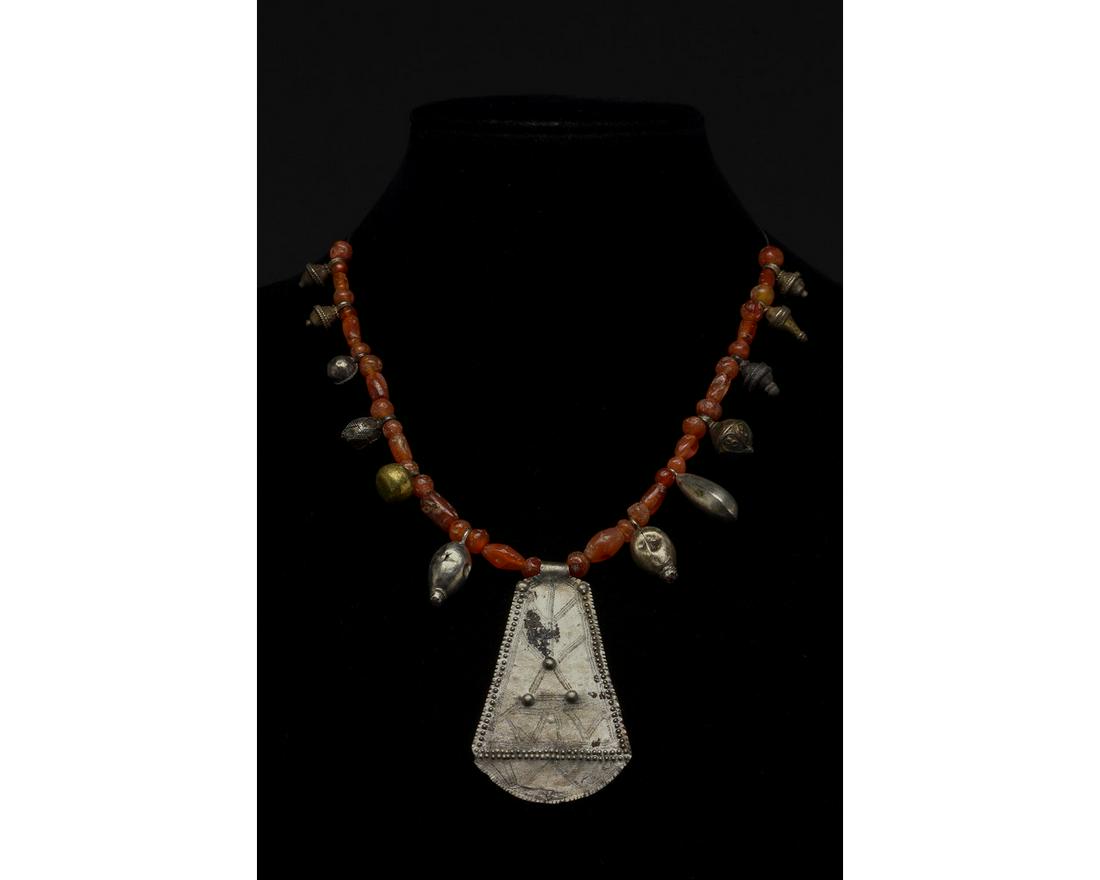 VIKING SILVER AND CARNELIAN NECKLACE - WEARABLE: AD 900-1100. Viking Age. An elegant necklace comprised of carnelian beads of various shapes (spheres, cylinders and barrels) and small silver pendants featuring engraved and applied decoration. The ce