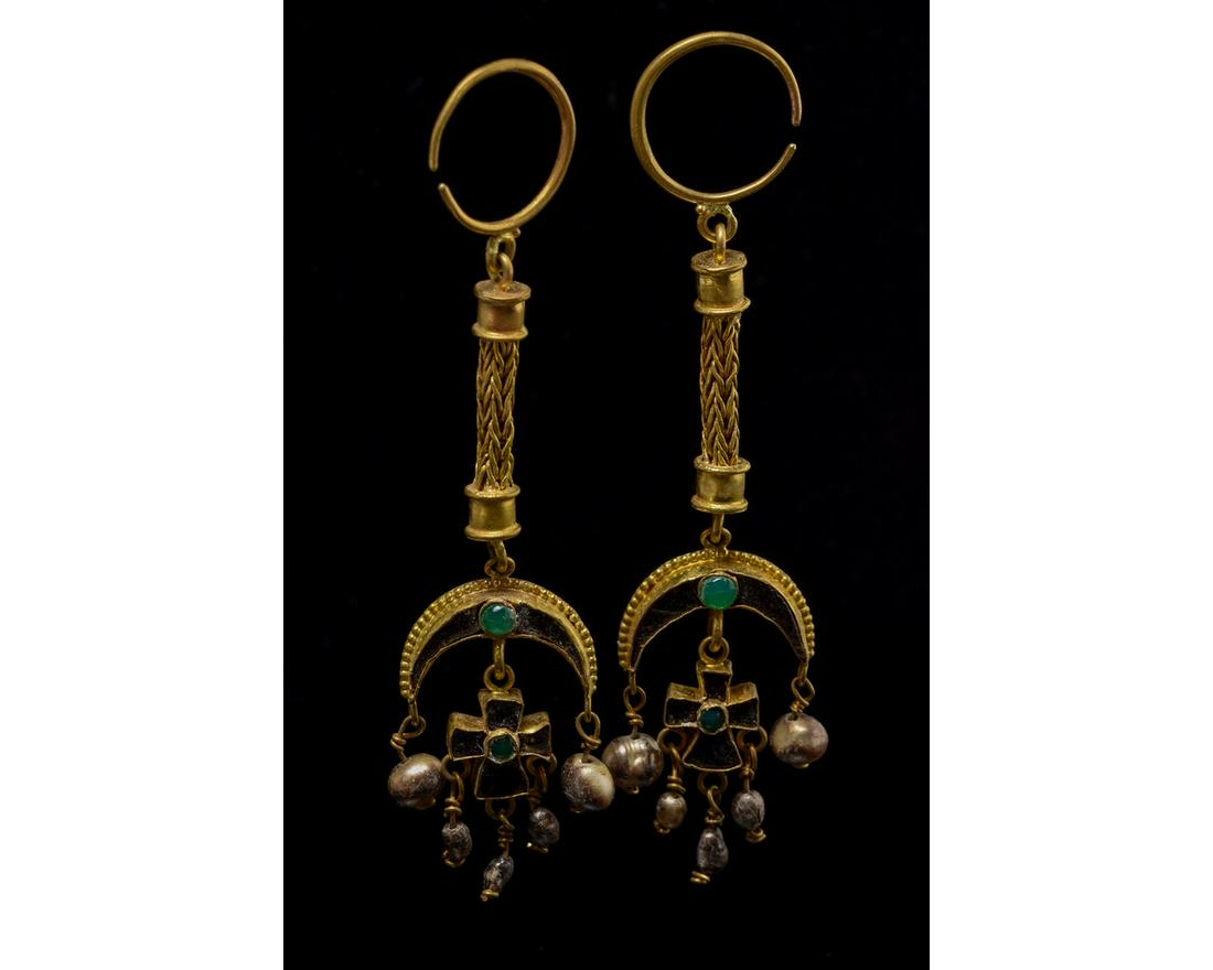 BYZANTINE GOLD PEARL, GARNET AND EMERALD EARRINGS: C. 1100-1300 AD. Byzantine. A stunning pair of elaborate gold earrings comprising an open, circular hoop, elongated woven cord connected to a crescent with applied gold spheres, garnet and emerald inl