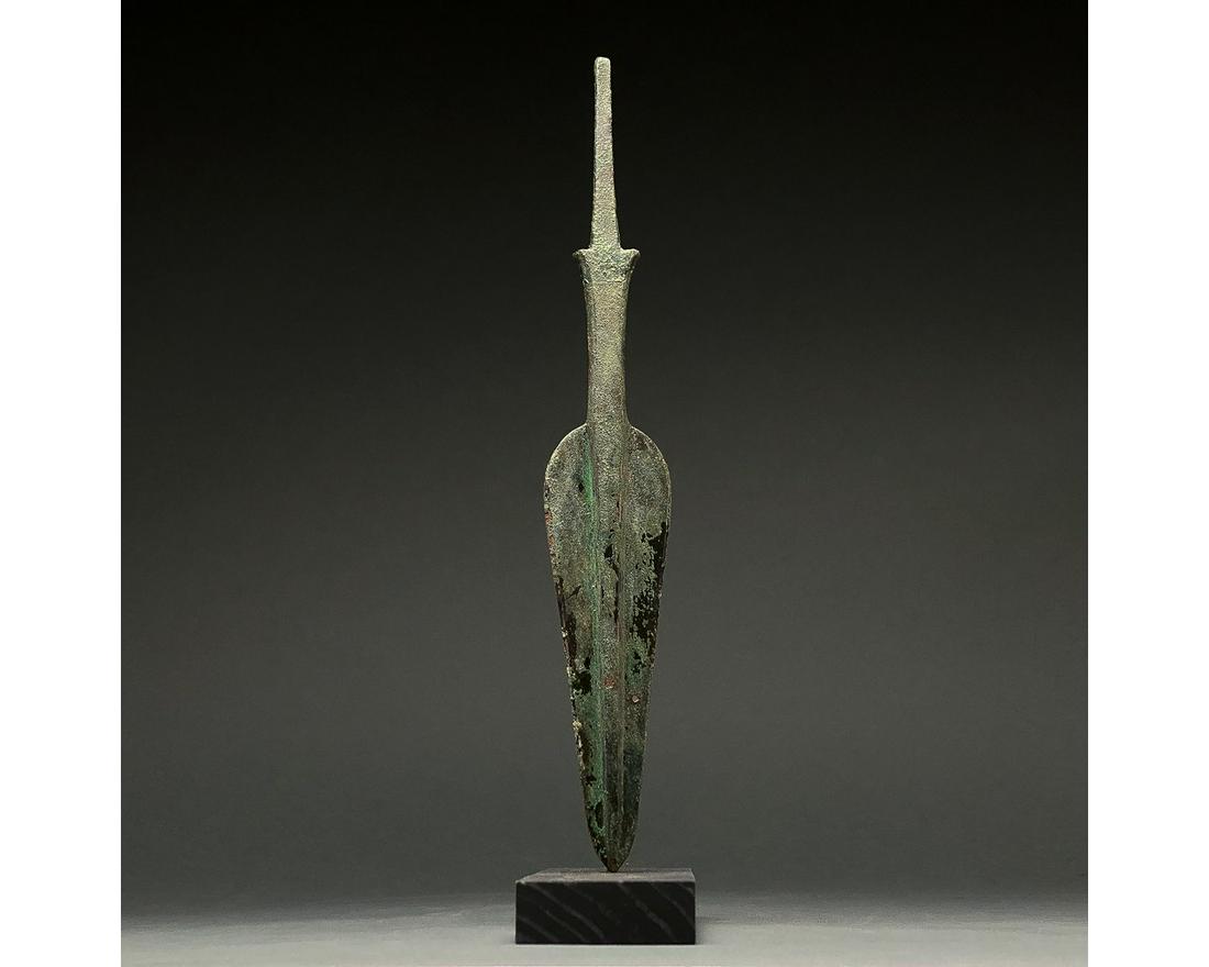 ANCIENT BRONZE LEAF-SHAPED SPEAR HEAD: 1200-700 BC, Greek Archaic Period. A bronze spearhead with a triangular, lentoid-sectioned blad with a raised midrib, short neck and tang. Bronze weaponry production flourished in western Asia, the Ae