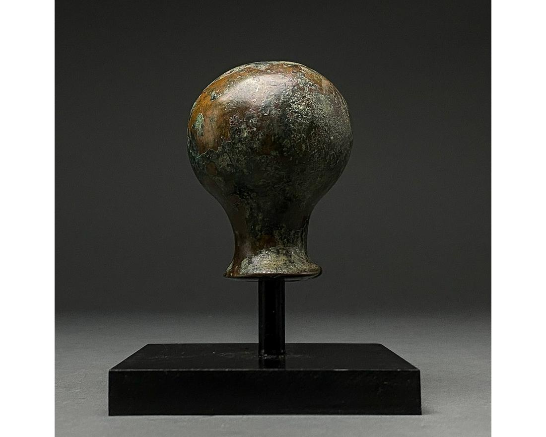 BRONZE AGE MACE HEAD ON STAND: 2000-700 BC, Luristan culture. Bronze macehead with spherical head, tapering shaft and flaring, circular aperture for the insertion of a wooden haft. Bronze weaponry production flourished from the 2nd