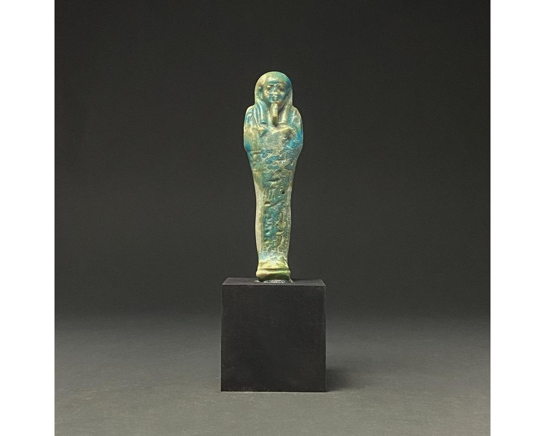 EGYPTIAN FAIENCE USHABTI ON STAND: Ca.1070-945 BC Egyptian, Early Third Intermediate Period. Beautiful blue faience ushabti figure wearing a tripartite wig and a false beard. Shabtis, also known as ushabtis, are Egyptian offerings inte