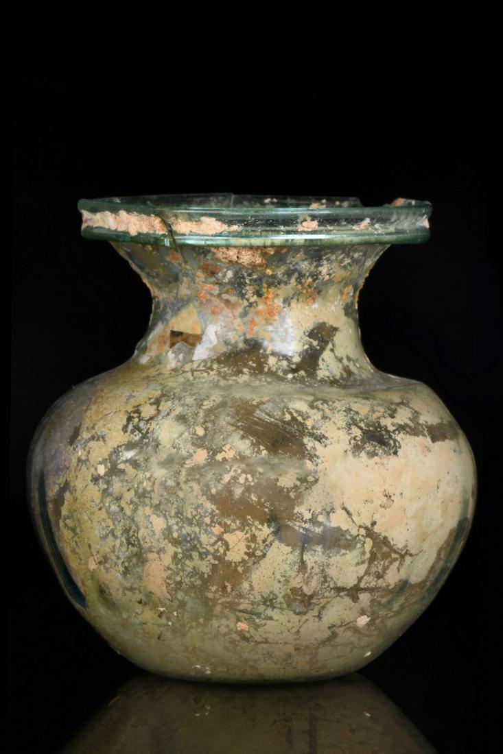 ROMAN GLASS FLASK: Ca. 200â€“300 AD. Roman. A free-blown sprinkler flask of transparent green glass with a spherical body, dipping at the shoulders, a short cylindrical neck and a wide, flanged profile mouth. Some