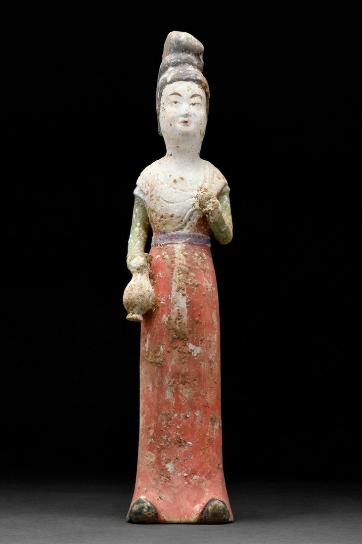 CHINESE TANG DYNASTY TERRACOTTA FEMALE ATTENDANT - TL: Circa 618-907 ADA mold-formed pottery tomb attendant figure in the form of a woman who is wearing a lengthy robe with a red-painted skirt, upper clothing in green, her left arm by her side holding a v