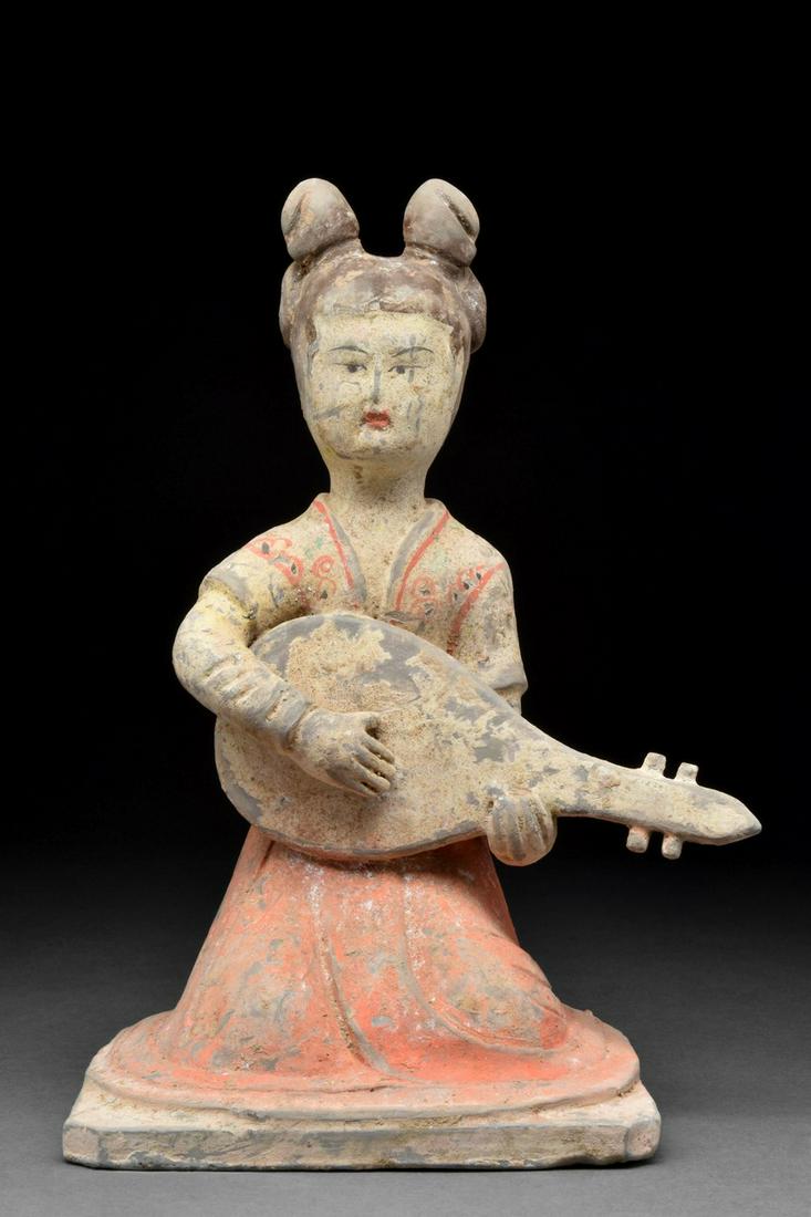 CHINESE TANG DYNASTY TERRACOTTA FEMALE MUSICIAN - TL TESTED: Ca. 618-906 AD A terracotta figure of a kneeling female musician wearing a long flowing gown with an orange skirt and cream bodice. The lady is delicately made up with red lip paint, delicate arching 
