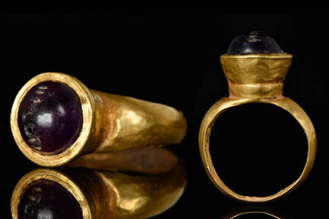 SASANIAN GOLD AND AMETHYST FINGER RING: Ca. 500-600 ADWith a heavy, plain hoop, flat on the interior, rounded on the exterior, expanding slightly to the angular shoulders, the high oval bezel set with an inscribed amethyst gemstone.For