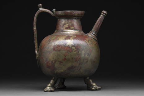 SELJUK COPPER BRASS TRIPOD JUG WITH CALLIGRAPHY: Persia, Ca. 12th-13th century AD A brass copper jug of a wide globular body, resting on hoofed tripod feet, gently tapering to a short cylindrical neck with a collared band and flared rim. The spout