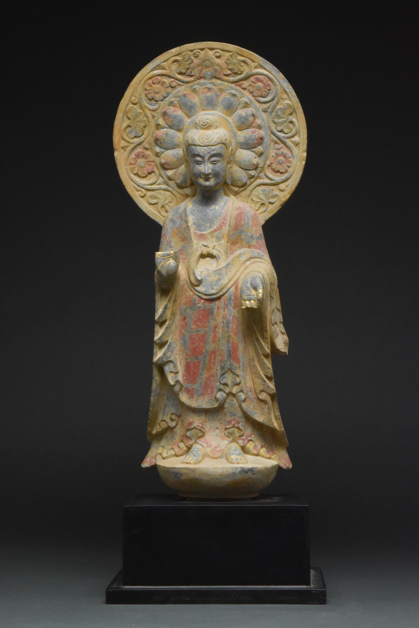 LIMESTONE FREESTANDING FIGURE OF A BODHISATTVA: Northern Qi Dynasty, Ca. 550-577 AD. The sculpture standing on a lotus plinth is depicted frontally, with legs slightly separated beneath the robe's hem, hands held in vitarkamudra, and the gesture of