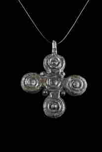 BYZANTINE BRONZE CROSS PENDANT: Ca. 1000-1300 AD. A bronze cross pendant featuring rounded arms with a dot in the center of each, and there are filigree granules in the corners. It also has a loop at the top for suspension. The reve