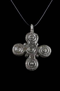 BYZANTINE BRONZE CROSS PENDANT: Ca. 1000-1300 AD. A bronze cross pendant featuring rounded arms with a dot in the center of each, and there are filigree granules in the corners. It also has a loop at the top for suspension. The reve