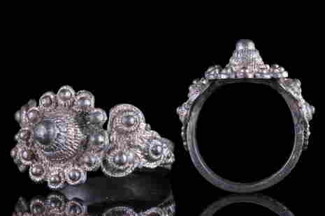 ELABORATE BYZANTINE SILVER RING: Ca. 600-800 AD. A silver finger ring featuring a ribbed hoop with an applied bezel with intricate knobbed filigree decoration and captivating shoulders embellished with trefoil plaques that mirror the