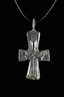 BYZANTINE BRONZE CROSS PENDANT: Ca. 600-800 AD. A cruciform bronze pendant depicting a stylized Jesus Christ during his crucifixion. His arms and legs are outstretched with nails driven through his hands, reflecting his suffering on