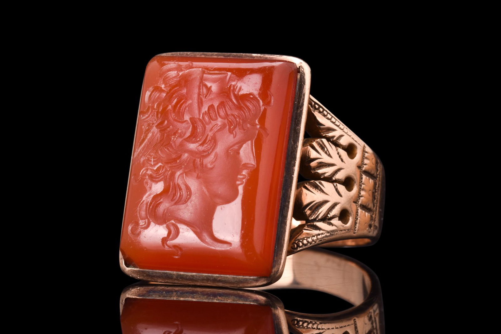 NEOCLASSICAL GOLD RING WITH GRYLLOS INTAGLIO: Ca. 1800 AD. A gold ring of a wide hoop, with its ornate detailing, speaks of the elegant craftsmanship of the era, while the large rectangular bezel allows for the striking intaglio to take center st