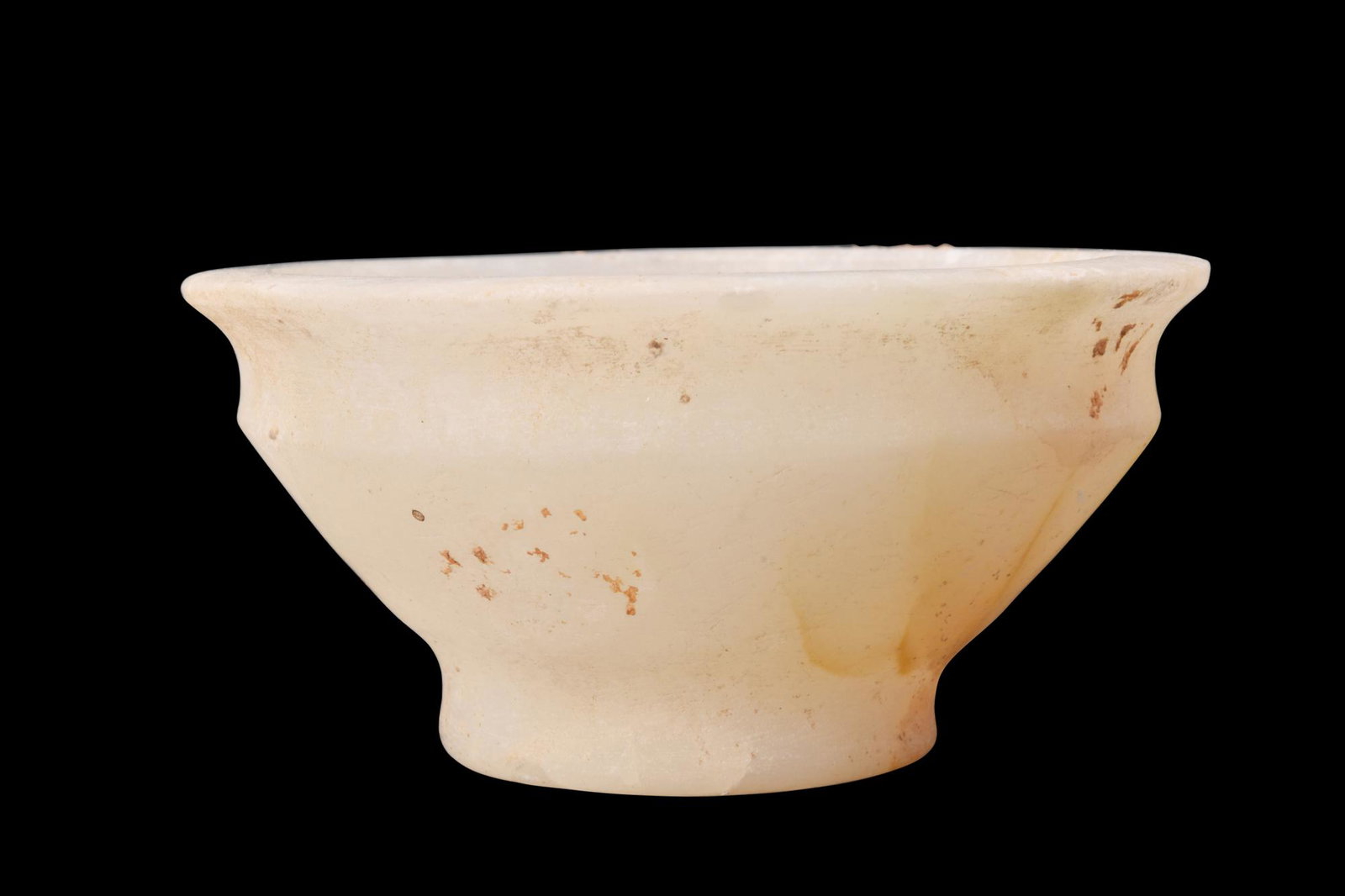EGYPTIAN ALABASTER BOWL: New Kingdom, ca. 1550-1070 BC.An alabaster bowl featuring smooth walls that gracefully curve into an everted rim and a rounded basin. The bowl rests upon a short foot, providing stability, and has a f