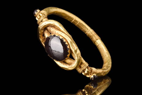 ROMANO-EGYPTIAN GOLD BRACELET WITH “HERCULES’ KNOT” SET WITH A GARNET: Ca. 1st century BC. A hollow-formed bracelet, crafted with meticulous artistry and adorned with captivating embellishments. This opulent piece features a central faux Hercules knot, skilfully