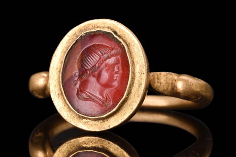 ROMAN GOLD RING WITH CARNELIAN PORTRAIT INTAGLIO: Ca. 300 AD. A gold finger ring with its band formed into a hoop with duck-head finials, which adds a unique touch to the design. The bezel cell is set with an oval carnelian intaglio, which depicts