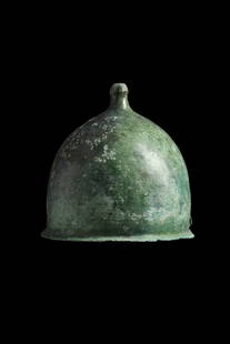 ROMAN BRONZE MONTEFORTINO HELMET - ex. Axel Gutmann: Ca. 1st century BC - 1st century AD. A relatively light bronze legionary helmet with a bulbous domed bowl, small crest knob with a flattened top, pierced at the centre for insertion of a crest pin;