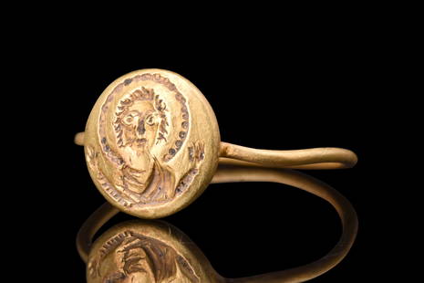 BYZANTINE GOLD RING WITH MARY ORANS: Ca. 600 AD. A gold ring comprised of a thin round-section hoop, and an applied circular bezel that is adorned with a representation of the bust of the Virgin Mary. The Virgin Mary is depicted facing