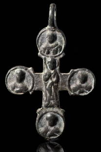 BYZANTINE BRONZE CROSS: Ca. AD 700-900.A double-sided bronze crucifix pendant featuring arms terminating in roundels, each adorned with a low relief bust of a saint. The pendant includes a suspension loop positioned at the t