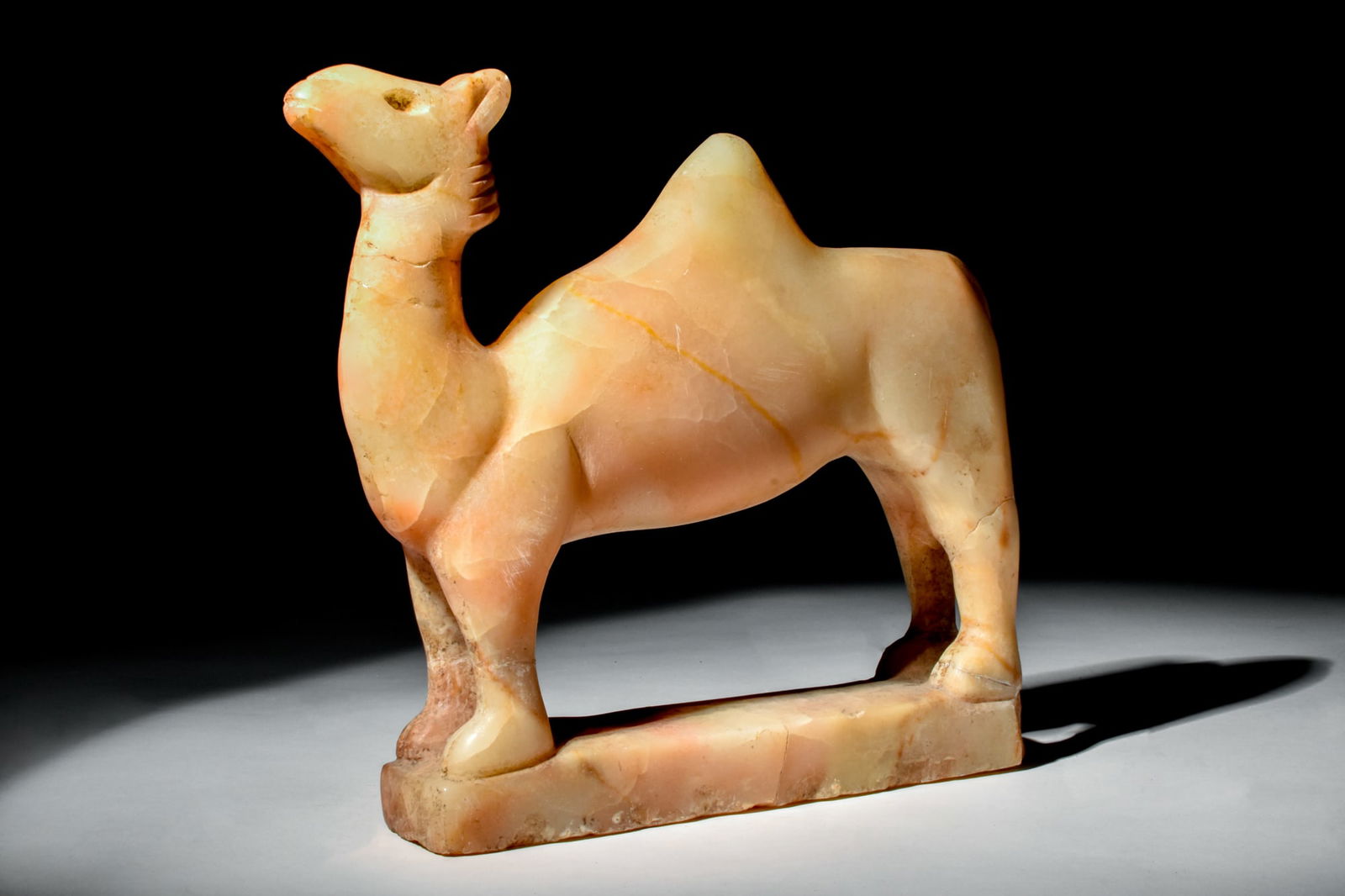 SOUTH ARABIAN ALABASTER CAMEL: Ca. 300 BC - AD 100.An alabaster carved figurine of a camel standing atop an integral, flat base. The animal stands in an erect pose with its head raised. Size: 200mm x 250mm; Weight: 2.2kg Provenance