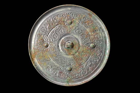 CHINESE TANG DYNASTY BRONZE MIRROR: Ca. AD 618-907 or later.A bronze mirror with a convexly curved and finely polished mirror face. On the reverse side of the mirror, a central raised boss commands attention, accompanied by four