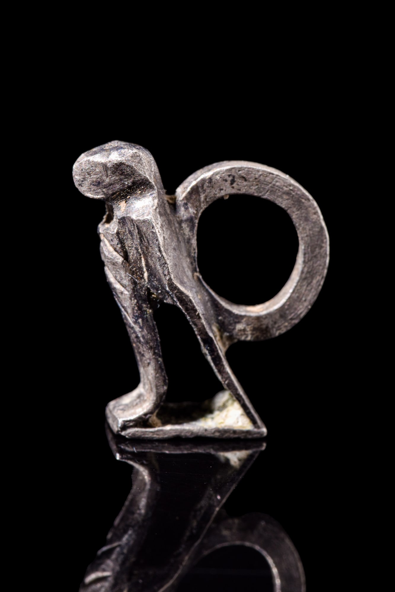 ROMANO-EGYPTIAN SILVER EAGLE PENDANT: Egypt, Ca. 30 BC - AD 300.A silver eagle with its wings gracefully folded, resting upon an integral and flat base. Completing the amulet is a suspension loop that extends from the back, allowing for c