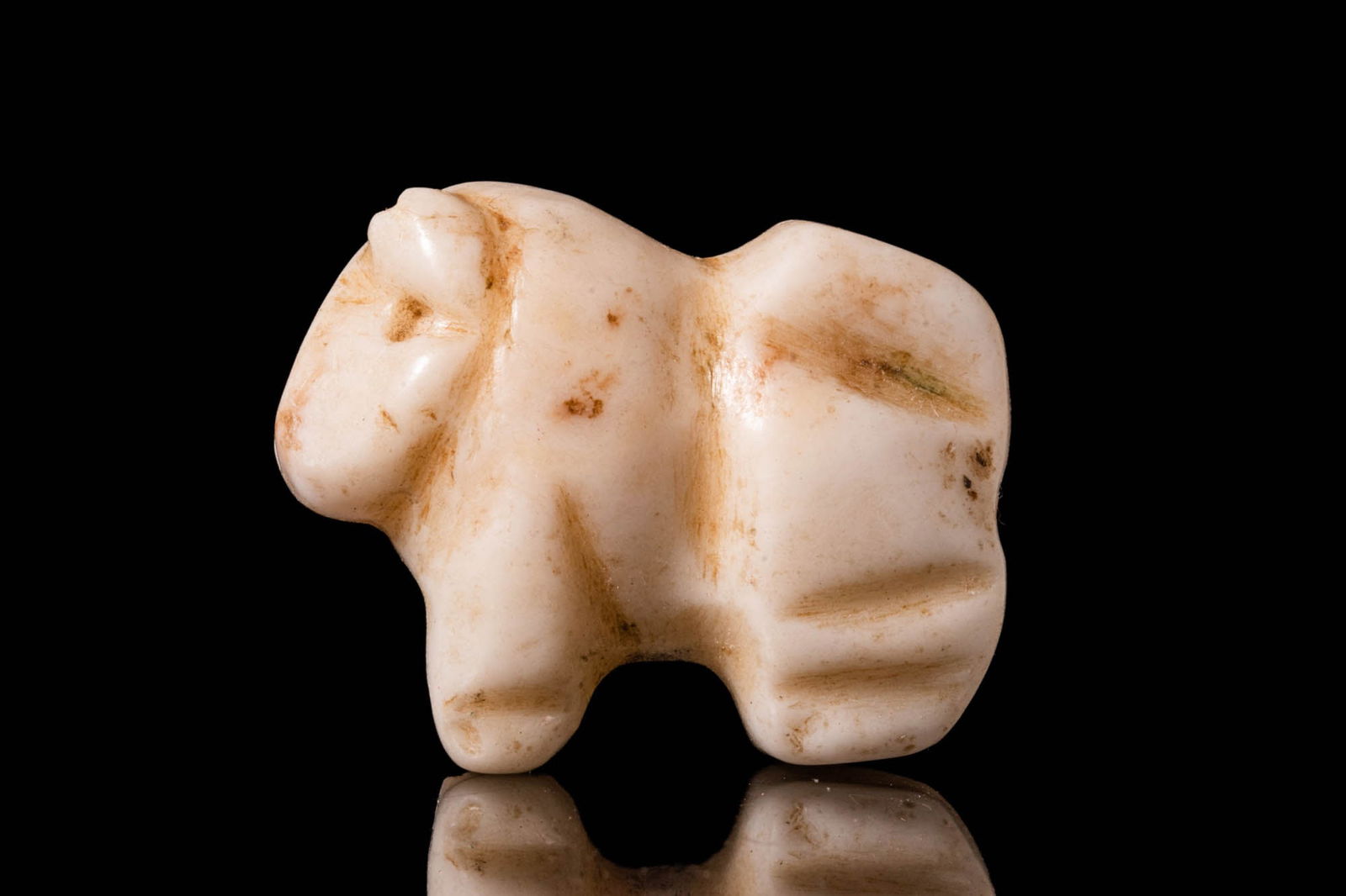 MESOPOTAMIAN WHITE STONE ZOOMORPHIC AMULET: Ca. 3500 - 2900 BC. A Sumerian white stone amulet in the form of a standing bull, with curved horns, drilled eyes and an incised snout. For similar see: Christie’s, live auction 2450, lot. 1. Size: