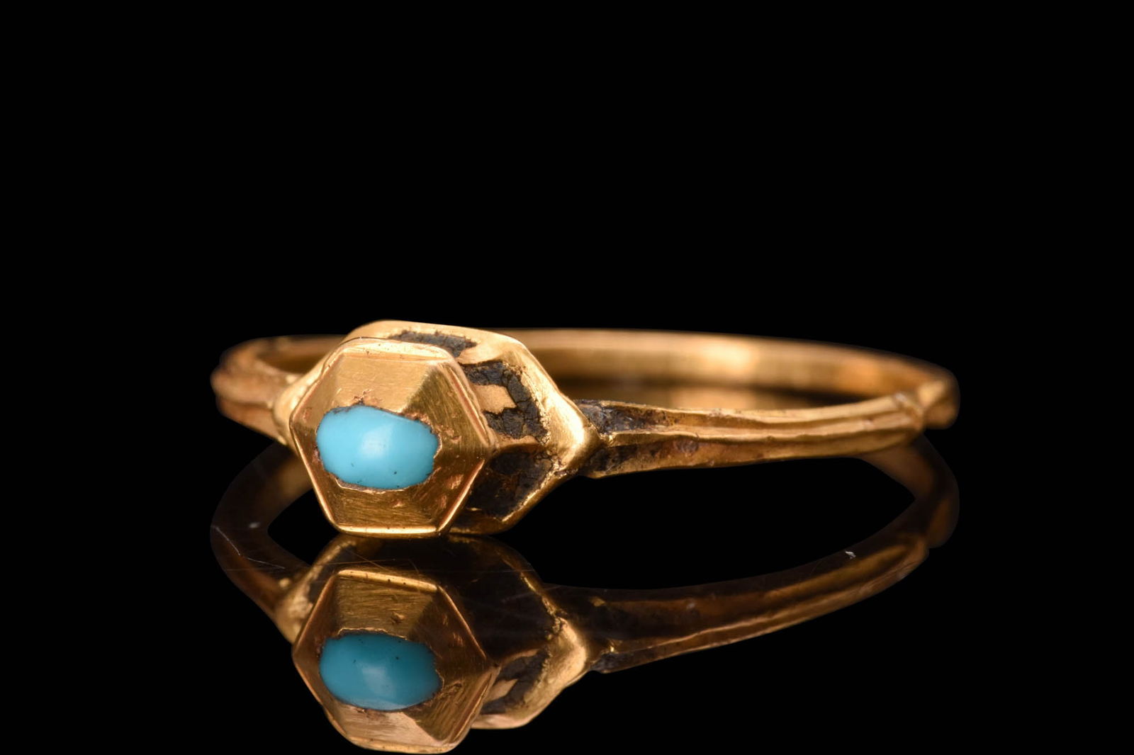 RENAISSANCE GOLD AND TURQUOISE RING: Ca. AD 1600.A gold finger ring featuring a thin, round hoop with a median rib at the shoulders. The centerpiece of the ring is its raised bezel, which holds a mesmerizing turquoise gem in a hexagonal