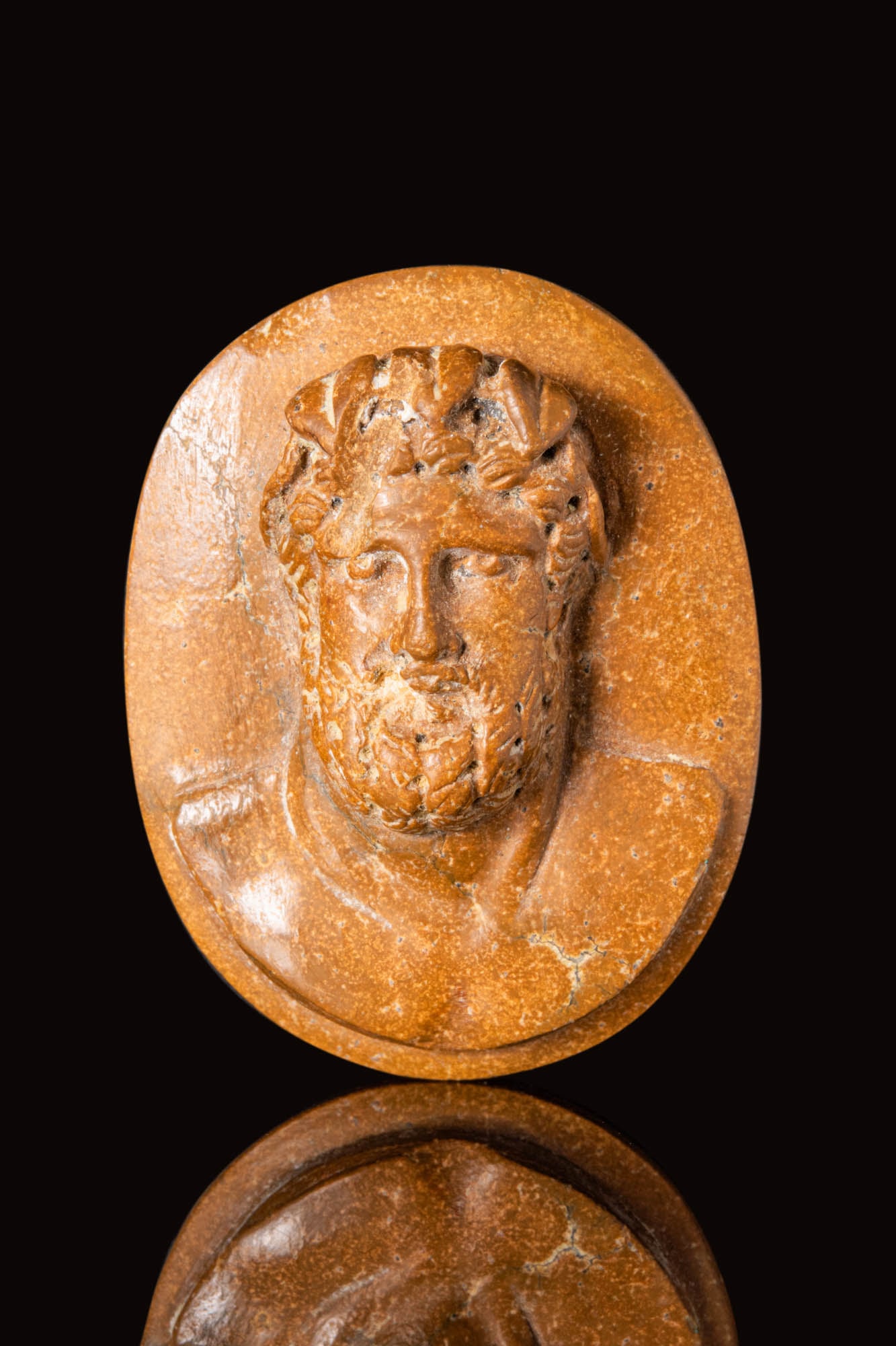 NEOCLASSICAL CAMEO DEPICTING A ROMAN EMPEROR: Ca. AD 1800 - 1900. A Neoclassical stone cameo depicting a Roman emperor or god made in a naturalistic manner. The figure has a straight nose with protruding eyes, hair that is surmounted by a crown o