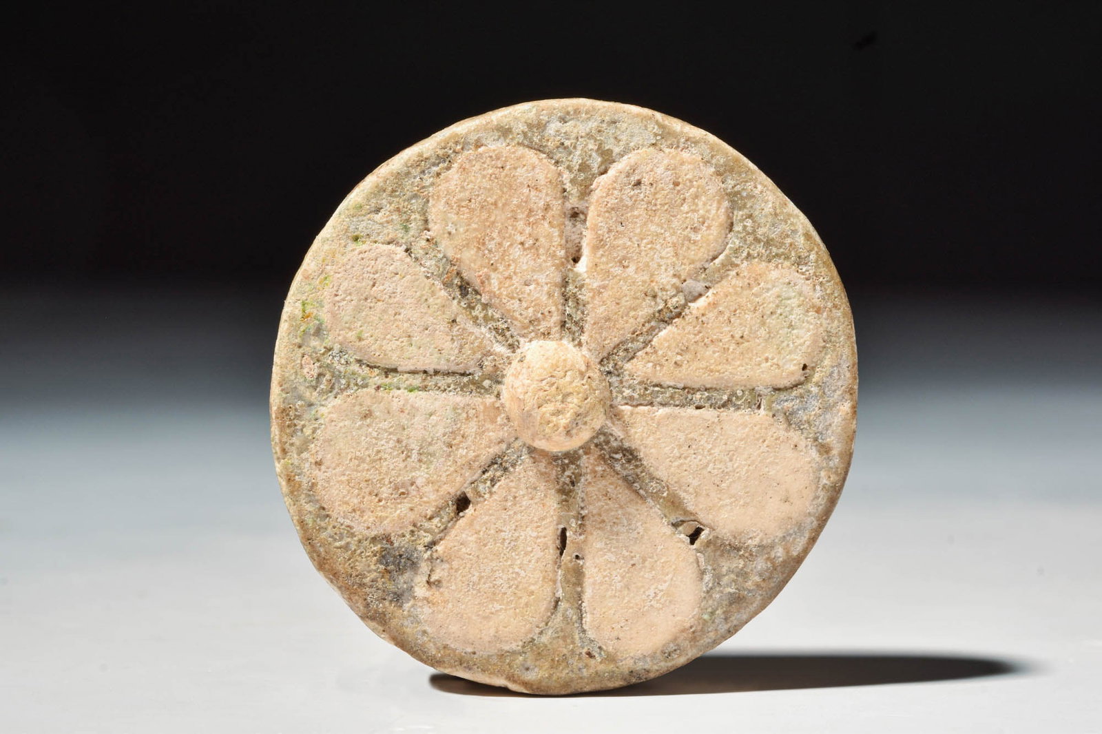 EGYPTIAN NEW KINGDOM FAIENCE ROSETTE INLAY: New Kingdom, 20th Dynasty, Ca. 1184 - 1153 BC.A glazed composition inlay in the form of a rosette, set with creamy white petals on a brown background with a yellow central boss. Thousands of similar r