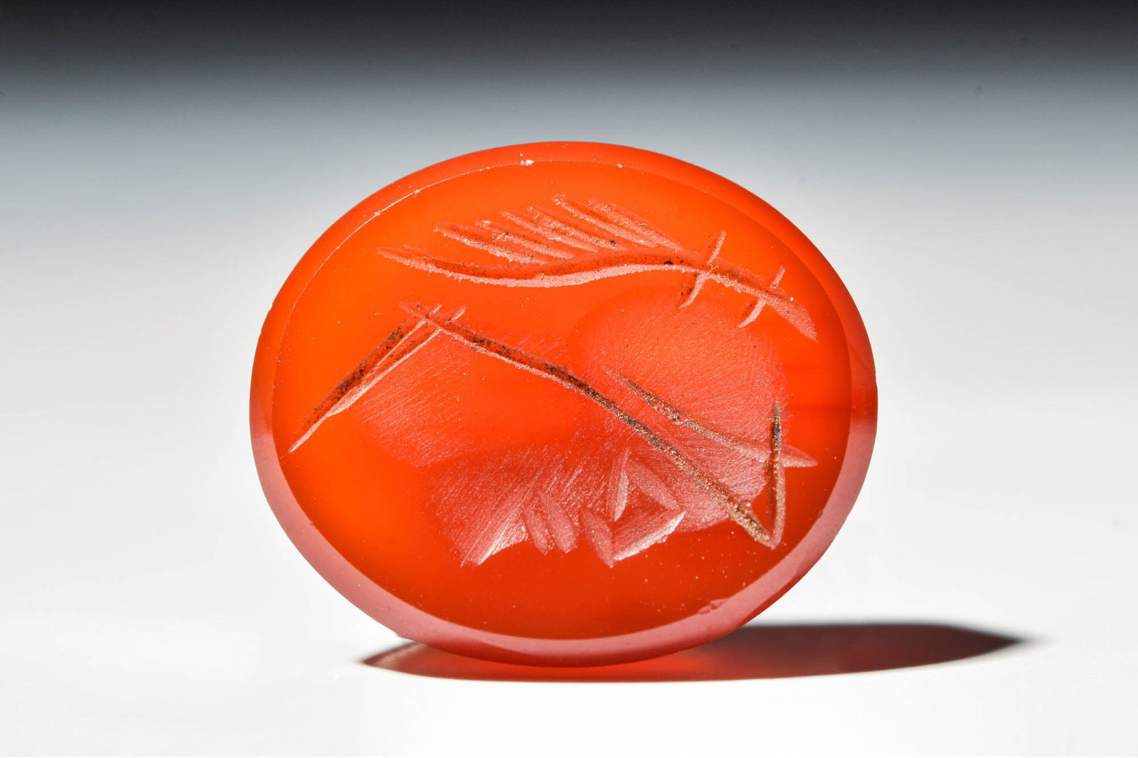 ROMAN CARNELIAN INLAY WITH BUST OF MARS: Ca. AD 100 - 300 .A carnelian intaglio carefully carved with the profile of the god Mars, facing right. The young, clean-shaven male wears an Attic helmet with a plume of feathers, characteristic of M