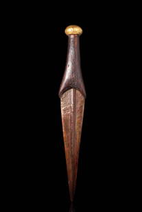 EGYPTIAN BRONZE DAGGER WITH GOLD POMMEL: New Kingdom, Ca. 1550 - 1069 BC. A cast-bronze dagger blade with a shallow midrib bearing several fullers, a tip, and sharpened edges. The tang is inserted into a wooden handle and connected to a